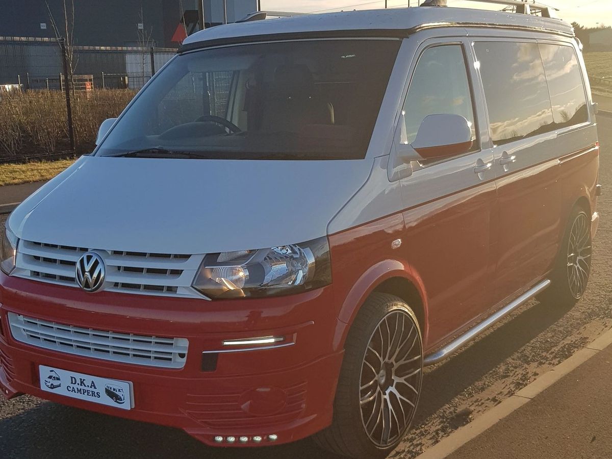 Red and white VW Transporter T5 camper with roof bars in low sun
