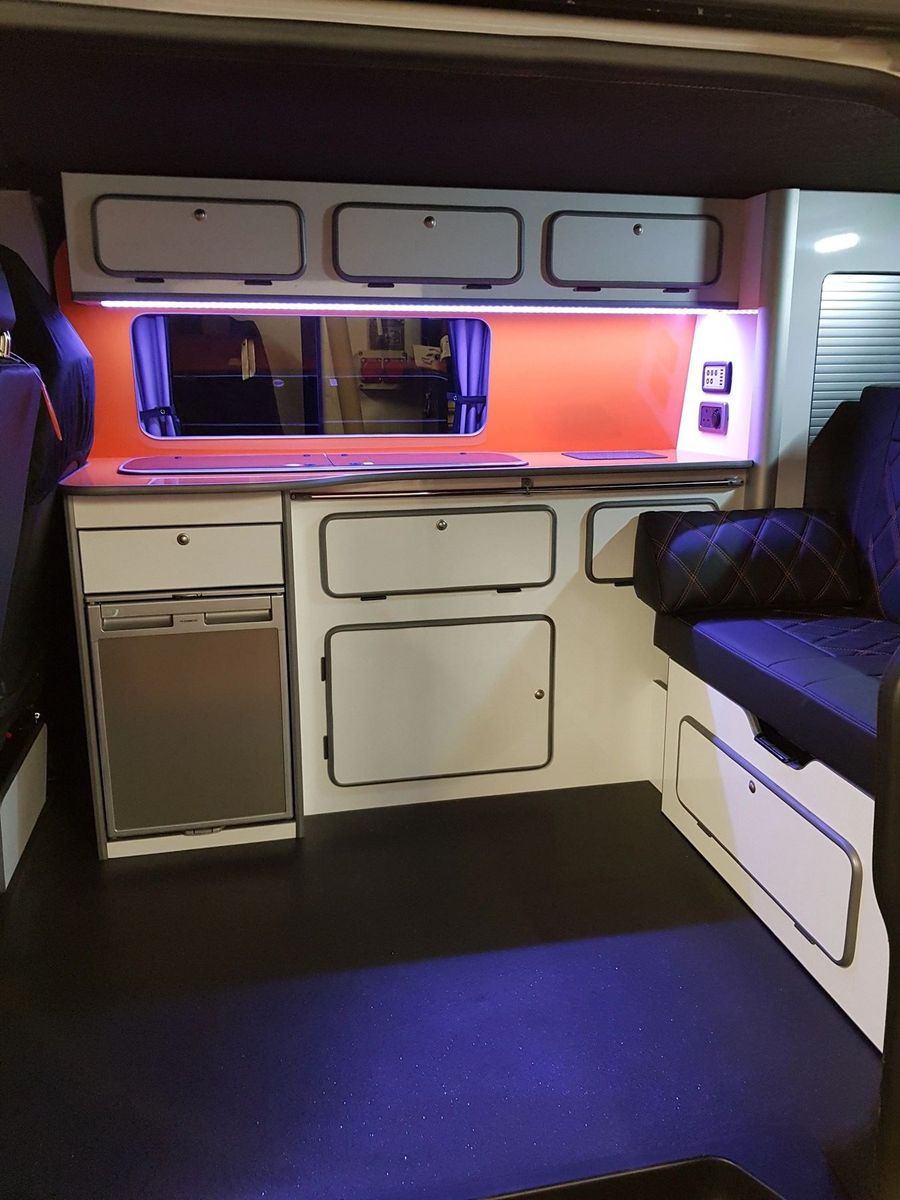 White units with an orange splashback and LED lighting