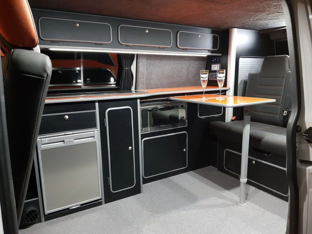 Dark grey kitchen units with an orange worktop and a pole-mounted table